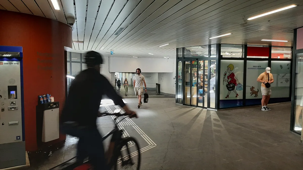Beschilderung und Velofahrer im Bereich der Bahnhofsunterführung in Dübendorf.